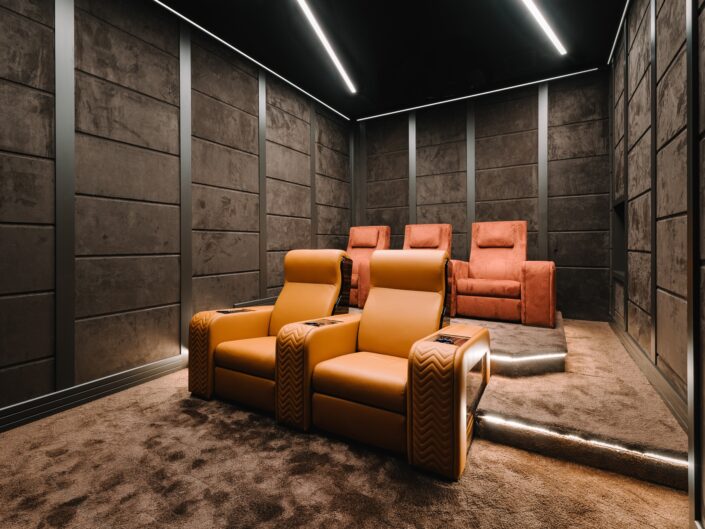 Home theatre in Milan with brown wall panels and colorful recliners